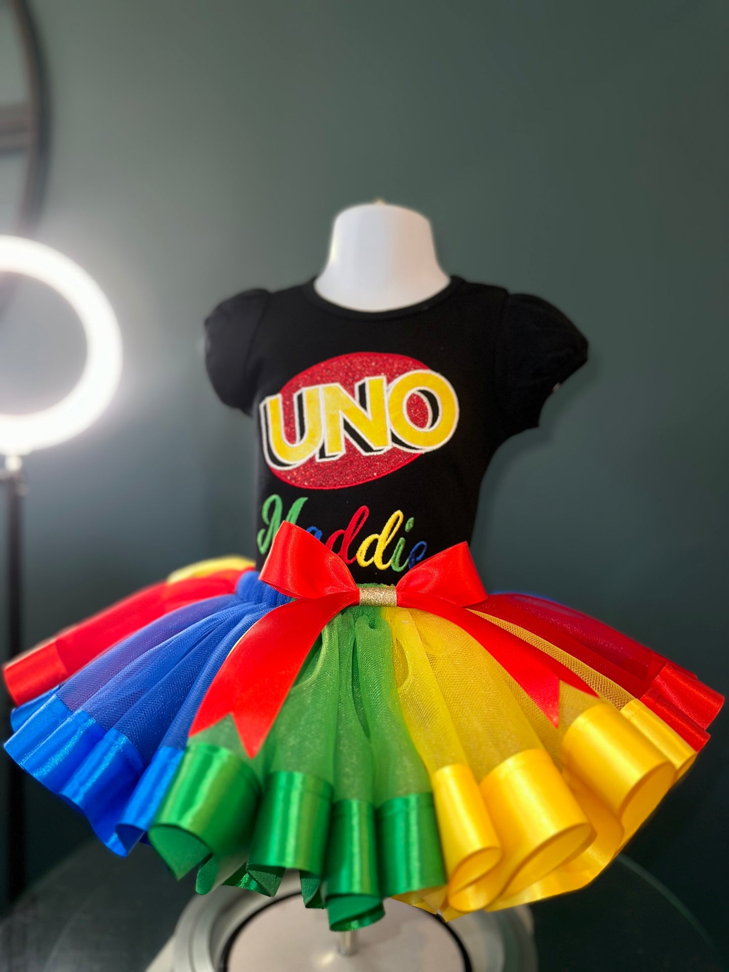 uno theme birthday outfit. personalized embroidery. black puff sleeve shirt and matching multi colored tulle skirt with waist bow