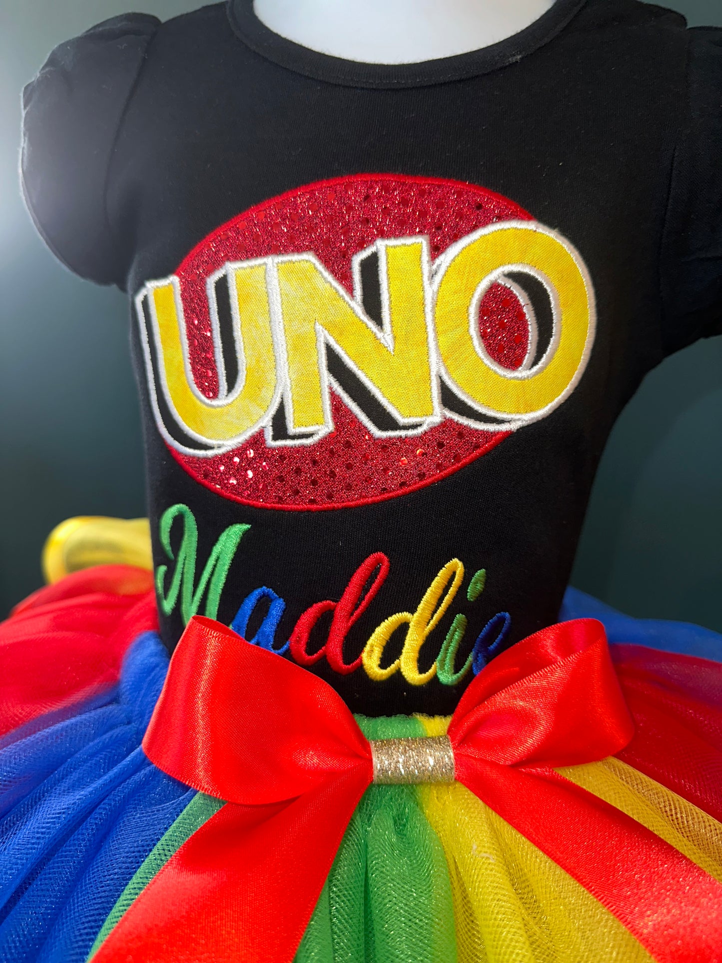 uno theme birthday outfit. personalized embroidery. black puff sleeve shirt and matching multi colored tulle skirt with waist bow
