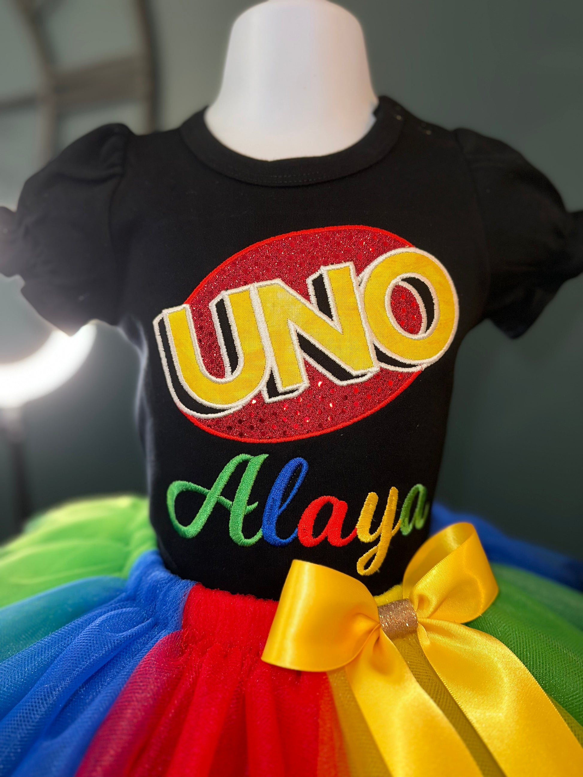 Personalized Uno theme Outfit with Uno logo. Puff sleeve black shirt with muti-colored double trim tulle skirt and matching waist bow. Theme and ideas