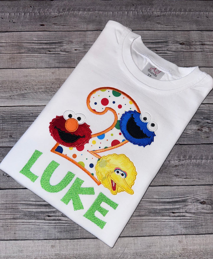 A white embroidered boys birthday shirt with playful red monster and friends characters, and the name &