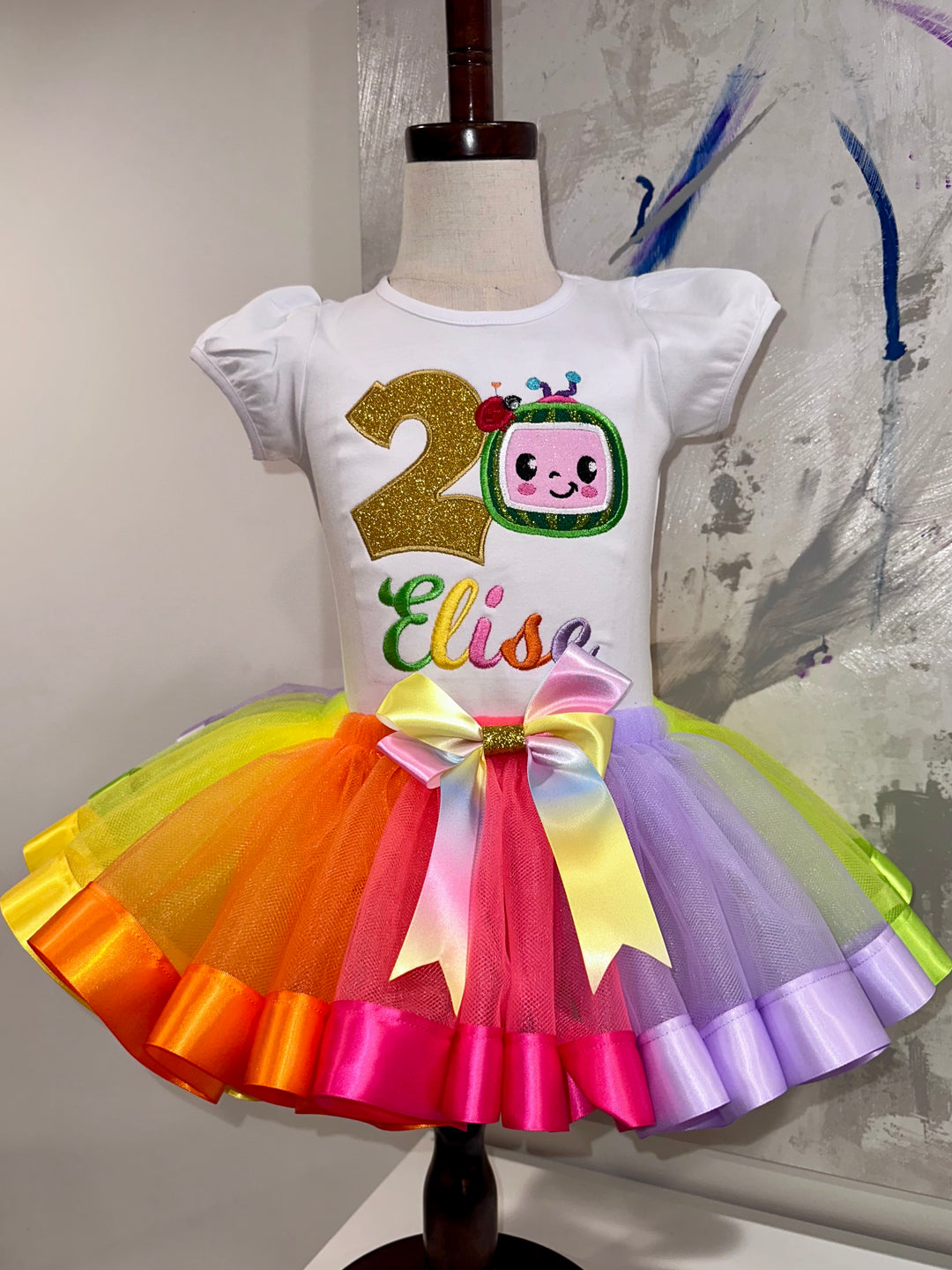 Personalized girls birthday outfit featuring a custom embroidered shirt with birthday age and name, paired with a colorful rainbow tutu skirt and matching bow. Boutique birthday outfit handmade by ECD Embroidery
