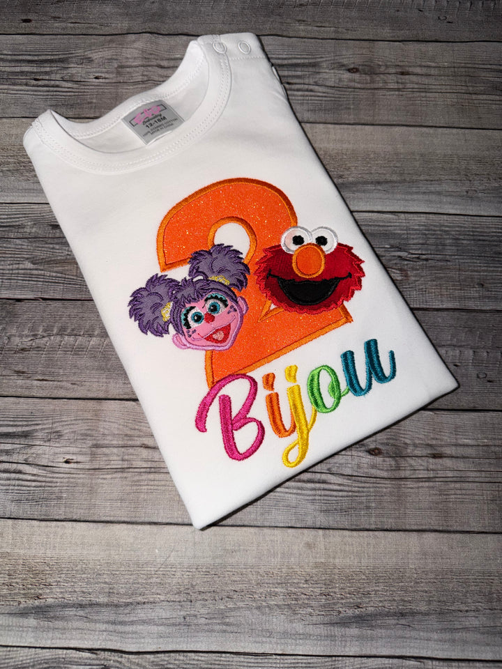 Embroidered shirt with colorful character design on a wooden surface