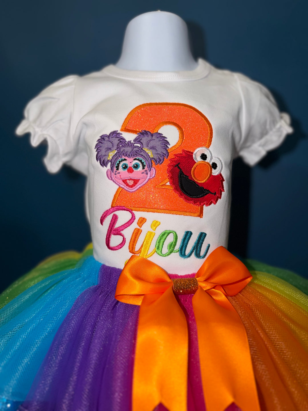 Colorful dress with Sesame Street-themed design on a mannequin against a dark background