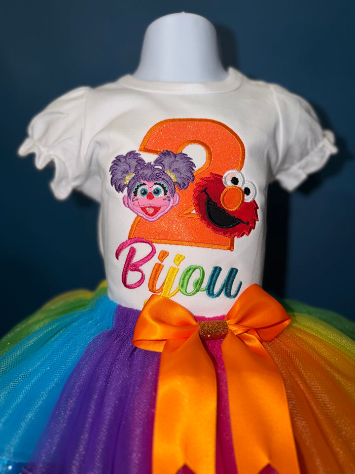 Colorful dress with Sesame Street-themed design on a mannequin against a dark background