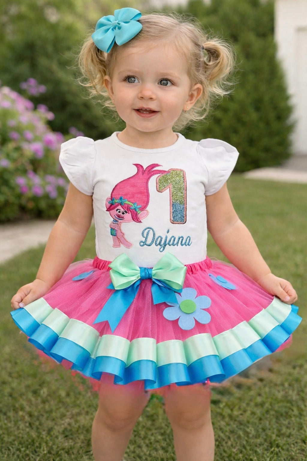 Child wearing a colorful birthday outfit with a tutu and character-themed shirt outdoors.