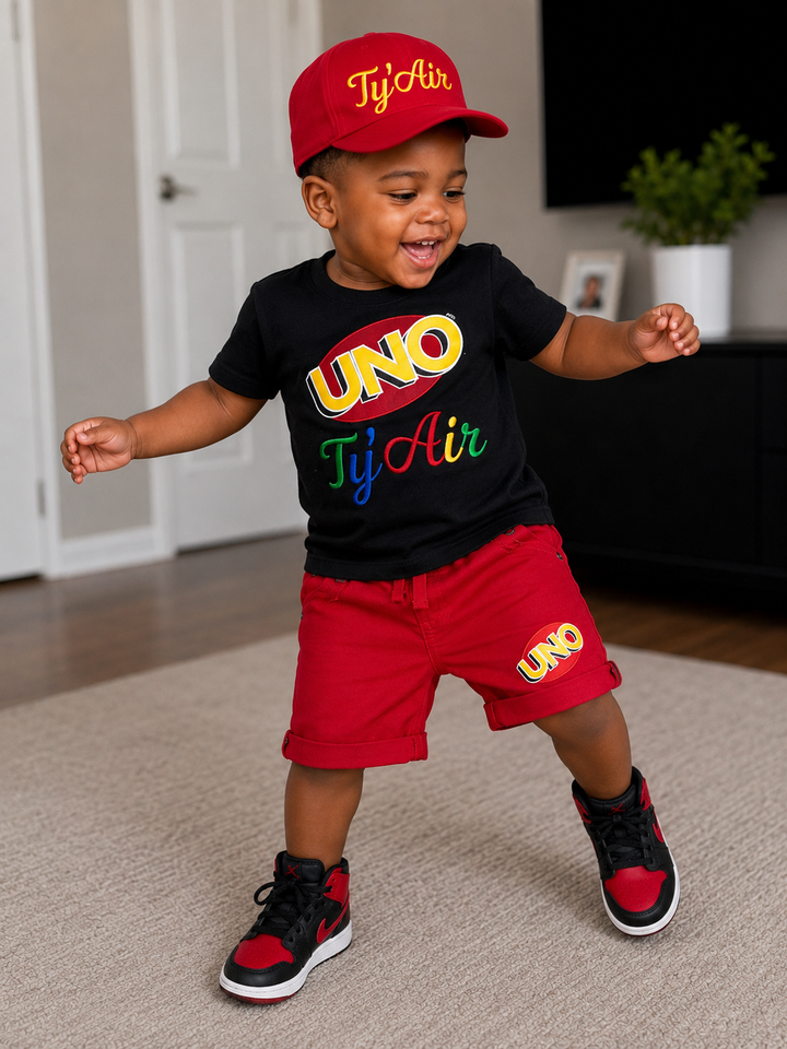 Custom UNO birthday outfit for a boy featuring a black embroidered UNO shirt, red shorts with UNO detail, and matching red birthday hat.