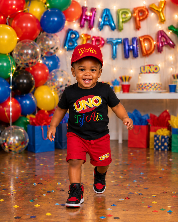 Personalized black UNO first birthday shirt paired with red shorts and matching embroidered UNO birthday hat for a toddler boy.