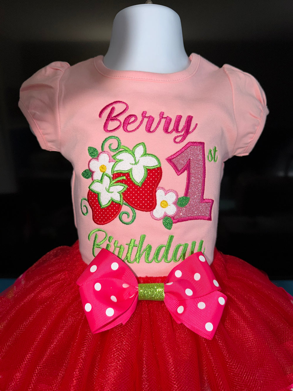 Pink birthday shirt with red tutu on a mannequin against a dark background