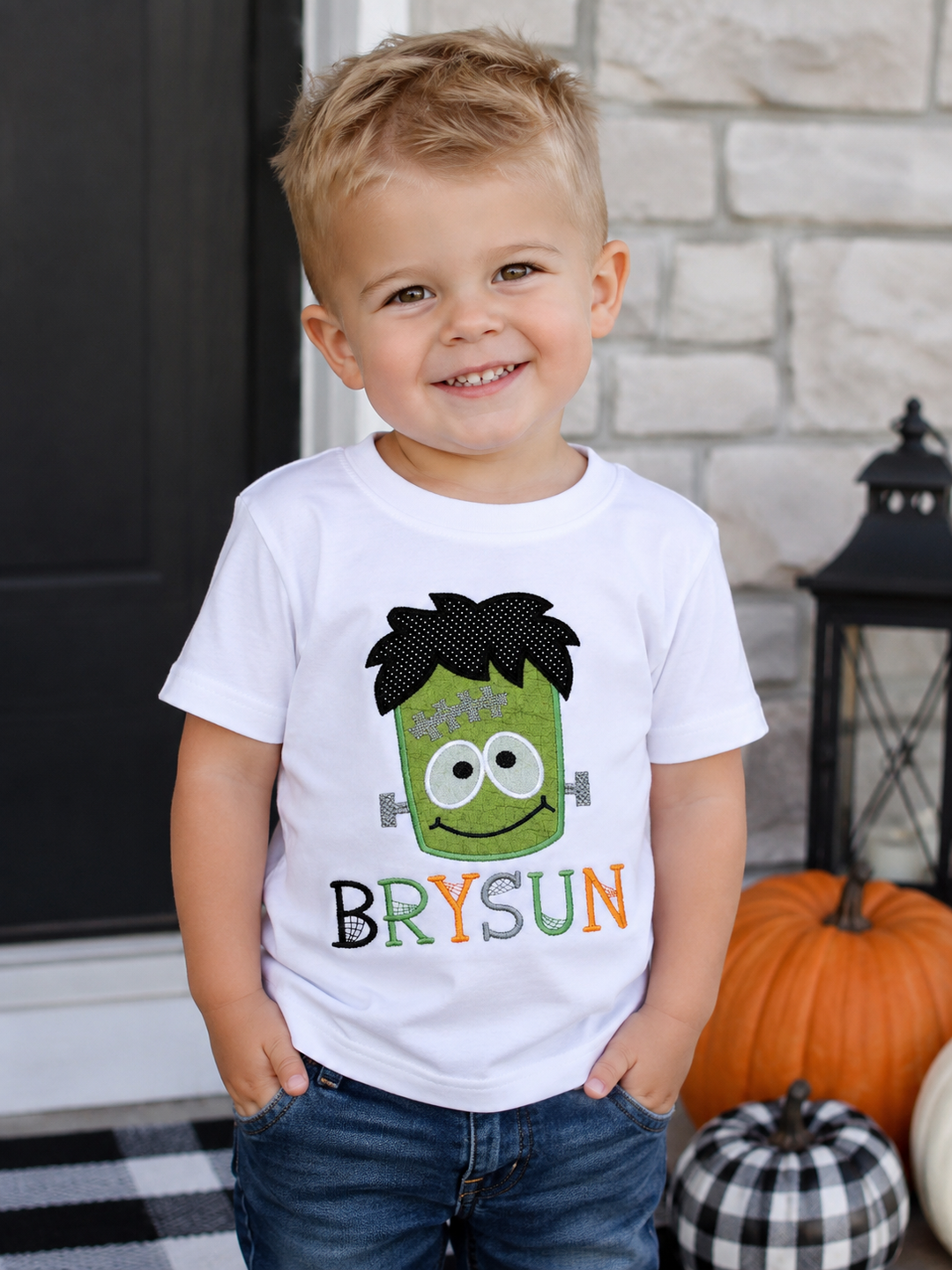Toddler boy wearing a personalized Frankenstein Halloween shirt featuring a colorful embroidered monster and the name Bryson